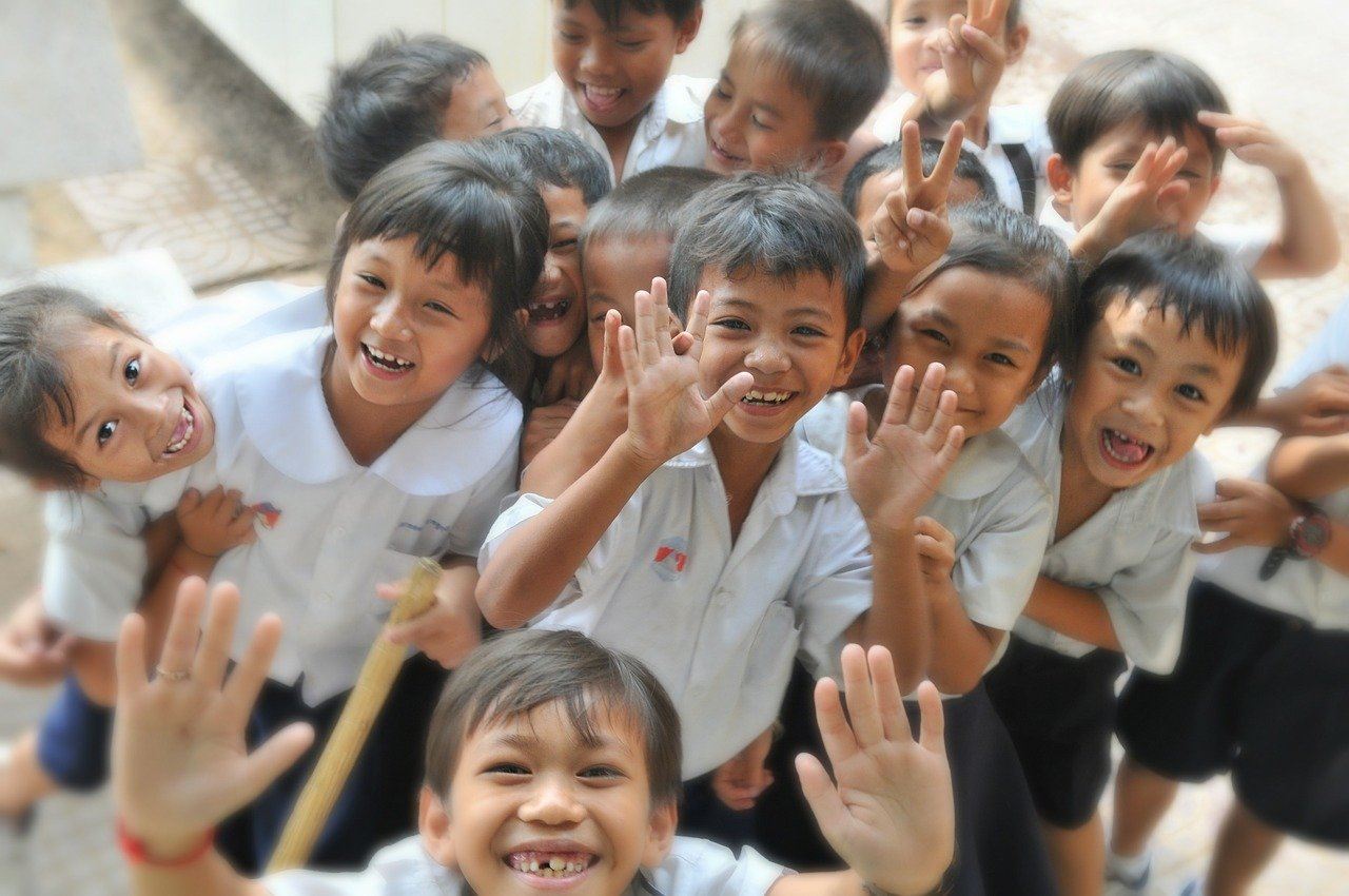 Asian school children smiling and waving at the camera